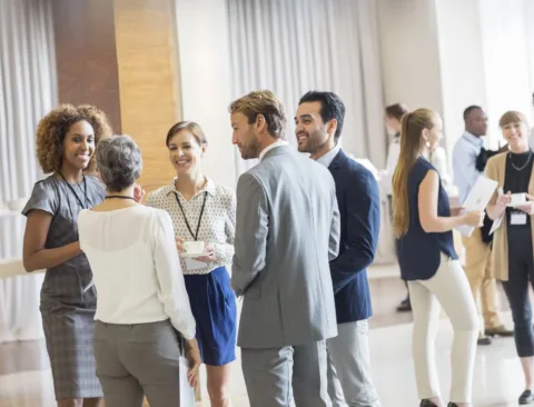 A group of professionally dressed people socializing and networking at an indoor Newburyport Bank event.